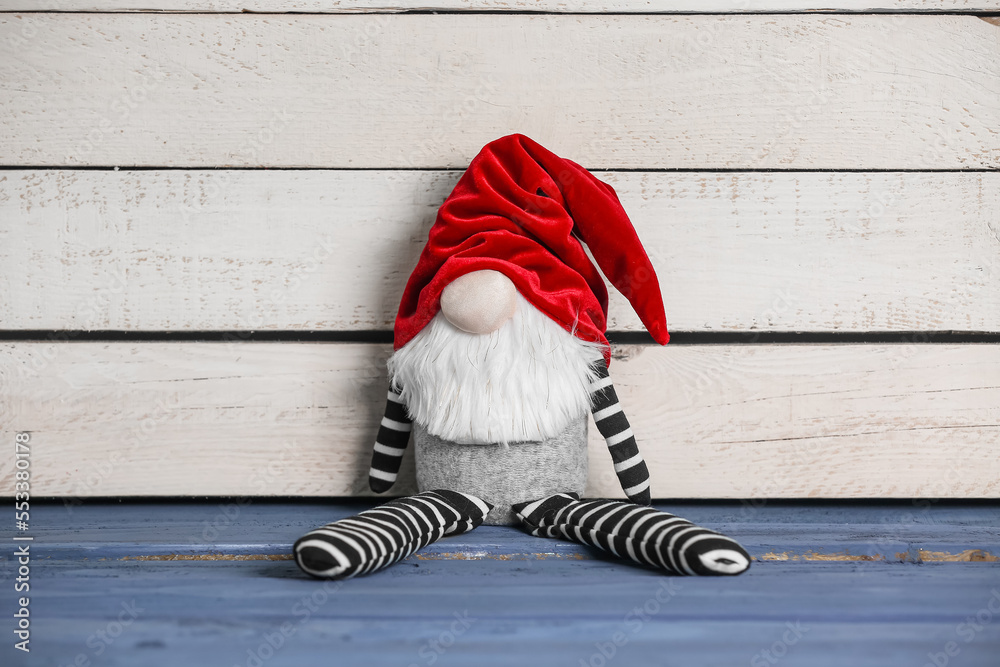 Funny Christmas gnome on color wooden table