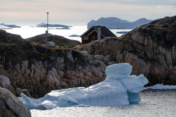 Casas de madera de colores en pueblo costero con icebergs flotando de fondo.