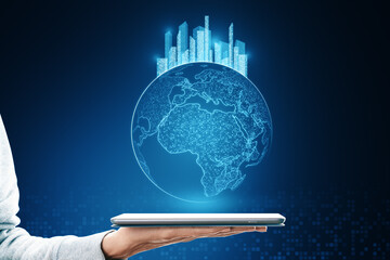 Poster - Close up of female hand holding tablet with glowing map with city hologram on blurry background. Abstract metaverse virtual reality concept building and digital map.