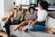 © Drobot Dean - African american family sitting on sofa at home