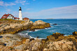 © Nicholas J. Klein - Ocean waves crash into rocky coastline with large lighthouse at top