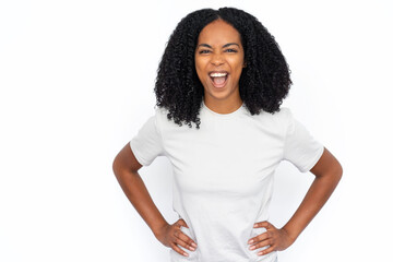 Wall Mural - Happy multiracial woman screaming. Excited young female model with dark curly hair in white T-shirt looking at camera with hands on waist, shouting loudly in excitement. Advertisement concept