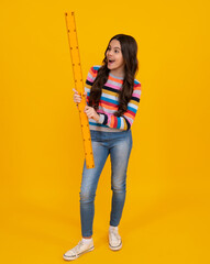Amazed teenager. School girl holding measure for geometry lesson, isolated on yellow background. Measuring equipment. Student study math. Excited teen girl.