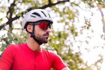 portrait of a young man wearing a helmet and cycling goggles in the middle of the forest, concept of freedom and sport in nature, copy space for text