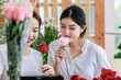 Millennial two Asian young professional female flower shopkeeper owner decorator standing holding red roses bunch bouquet in plastic wrapped smiling sending to customer celebrating valentine day
