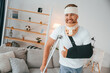 © standret - Smiling, showing thumb up. Man with crutches is at home indoors. Having injuries
