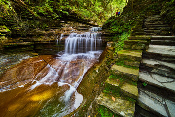 Wall Mural - Stone staircase passes by stunning waterfall in Upstate New York with couple in distance