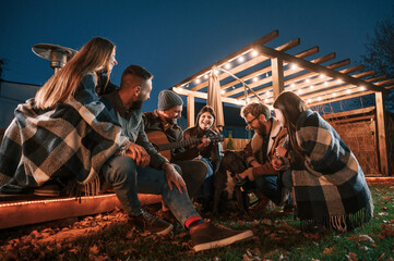 Wall Mural - Having fun with dog. Group of people is spending time together on the backyard at evening time