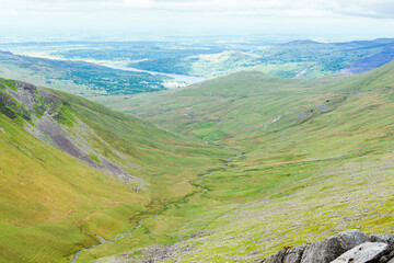 Wall Mural - Climbing up mountain range in North Wales, United Kingdom. Rural landsapes, green grass, cloudy sky, selective focus