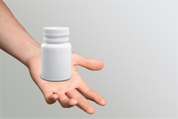 Canvas Print - Person's hand with blank medical plastic bottle for pill.