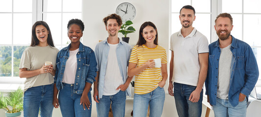 Group portrait happy smiling diverse mixed race people friends in casual clothes standing looking at camera. Someone drinking coffee or tea. Friendship, hanging out, lifelong friends concept.