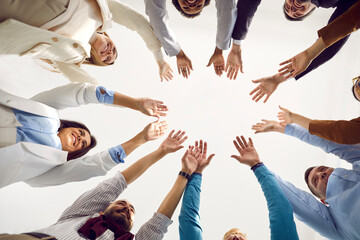 Team of business people celebrating teamwork. Group of happy people standing in circle, putting hands together and smiling. Teamwork, unity, partnership concept. Low angle bottom view, shot from below