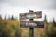 vintage and rustic wooden signpost with the weathered text quote nourish flourish, outdoors in nature. blurred out forest fall colors in the background.