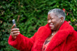 Senior woman wearing red fur coat and using phone