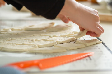 Wall Mural - A close-up view of the hands of a housewife in the process of cooking baursaks in the kitchen.