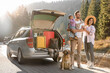© New Africa - Parents, their daughter and dog near car outdoors. Family traveling with pet