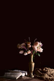 Fototapeta  - a bouquet of white roses, with the addition of lavender, sprigs of barberry to the flower arrangement. a bouquet of flowers in a vintage vase on a dark background with an open book on the table