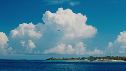 Wall Mural - Maldivian seascape with fluffy cumulus clouds and green island on the horizon