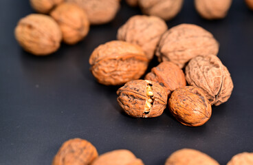 Closeup of walnuts on a black background with one open nut