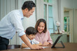 © visoot - Little boy taking online class with parents helping him at home,Boy is writing in his book.