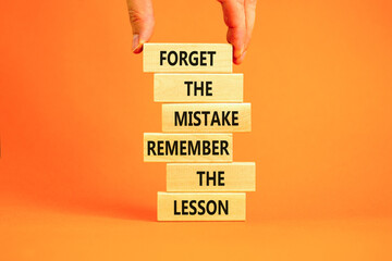 Lesson from mistake symbol. Concept words Forget the mistake remember the lesson on wooden blocks on a beautiful orange table orange background. Businessman hand. Business lesson from mistake concept.