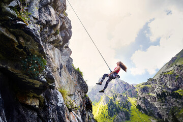 Wall Mural - Woman athlete climbing on the high rock in the mountains