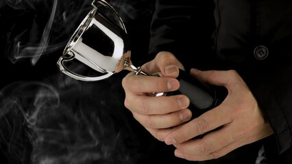 Wall Mural - male hand holding silver trophy on black background with smoke