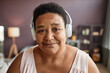 Candid closeup portrait of black senior woman wearing headphones and smiling at camera