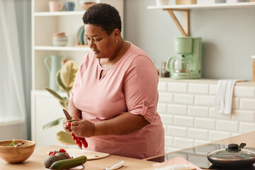 Waist up portrait of senior black woman cooking healthy salad in cozy home kitchen, copy space