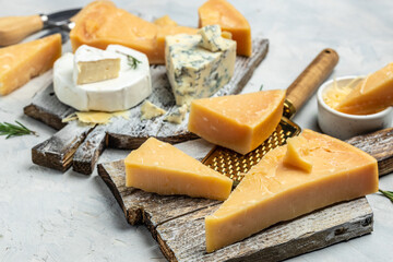 Sliced and grated parmesan cheese. set of hard pieces of parmesan cheese with knifes on a light background. top view