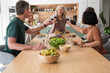 © PhotoAlto - Group of diverse senior friends making a toast while having dinner at home