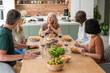© PhotoAlto - Group of diverse middle-aged friends sharing stories while having lunch at home