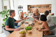 © PhotoAlto - Mid-shot of diverse group of co-workers making a toast while gathered at home for lunch