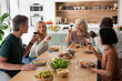 © PhotoAlto - Mid-shot of diverse group of co-workers making a toast while gathered at home for lunch