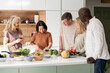 © PhotoAlto - Group of diverse middle-aged friends chatting at kitchen island while cooking meal