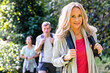 © PhotoAlto - Mid-shot of blonde middle-age woman with backback hiking with her diverse group of friends in the woods