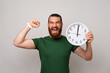 Powerful young man is happy he got all he want in time while holding a clock and making the winner gesture.