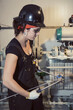 © Designpics - Female trades worker bending tubing to install fuel gas regulators in a control shack; Innisfail, Alberta, Canada