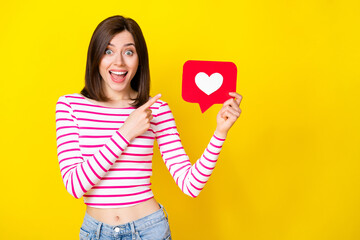 Sticker - Photo of astonished millennial girl arm hold finger point red paper card sign empty space isolated on yellow color background