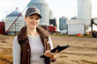 © Designpics - Portrait of mature woman working on her farm, holding a tablet computer and standing in front of grainery; Alcomdale, Alberta, Canada