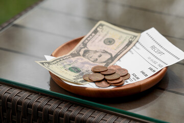 Wall Mural - Tips and receipt on wooden table, closeup