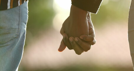 Close-up of hands joining together with sunlight flare in the background. Beautiful romantic moment between two lovers2