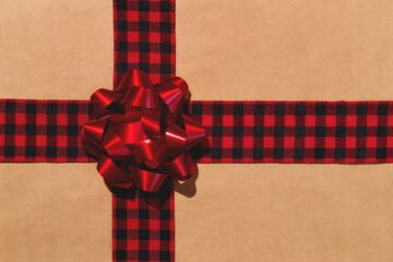 Black Buffalo Plaid gift ribbon and red bow on brown craft wrapping paper