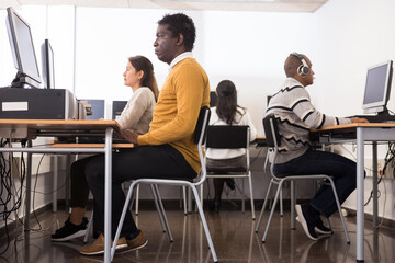 Wall Mural - Portrait of positive young adult man studying in computer class at library