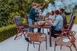 © .shock - A group of young diverse people having dinner on the terrace of a modern house in the evening. Fun for friends and family. Celebration of holidays, weddings with barbecue.