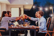 © .shock - A group of young diverse people having dinner on the terrace of a modern house in the evening. Fun for friends and family. Celebration of holidays, weddings with barbecue.