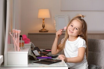 Wall Mural - Adorable little girl applying makeup at dressing table indoors