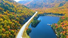 Aerial Fly Over Blue Lake And Peak Fall Foliage Mountains Of New Hampshire Along Road With Tourist Overlook