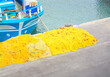 Yellow fishing nets on the pavement next to the boat