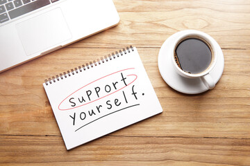 support yourself, motivational and inspirational words in notebook on table with laptop and cup of coffee.